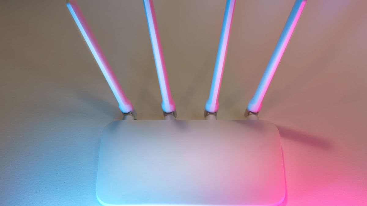 Antenleri mavi ve pembe ışıkla aydınlanmış beyaz bir Wi-Fi modemi